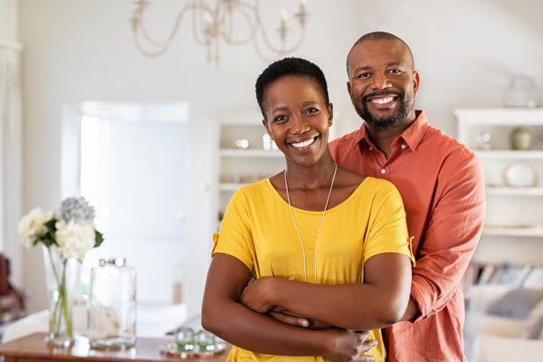 a couple smiles at the camera as they embrace each other in their nice kitchen