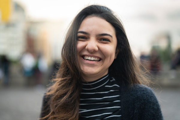 young woman in a striped turtleneck smiles at the camera