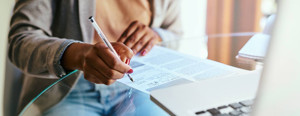 A person sitting at a table filling out paper forms