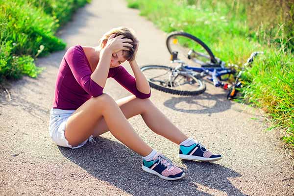 Woman with short hair with head injury after biking on bicycle. Sport, healthcare and people concept