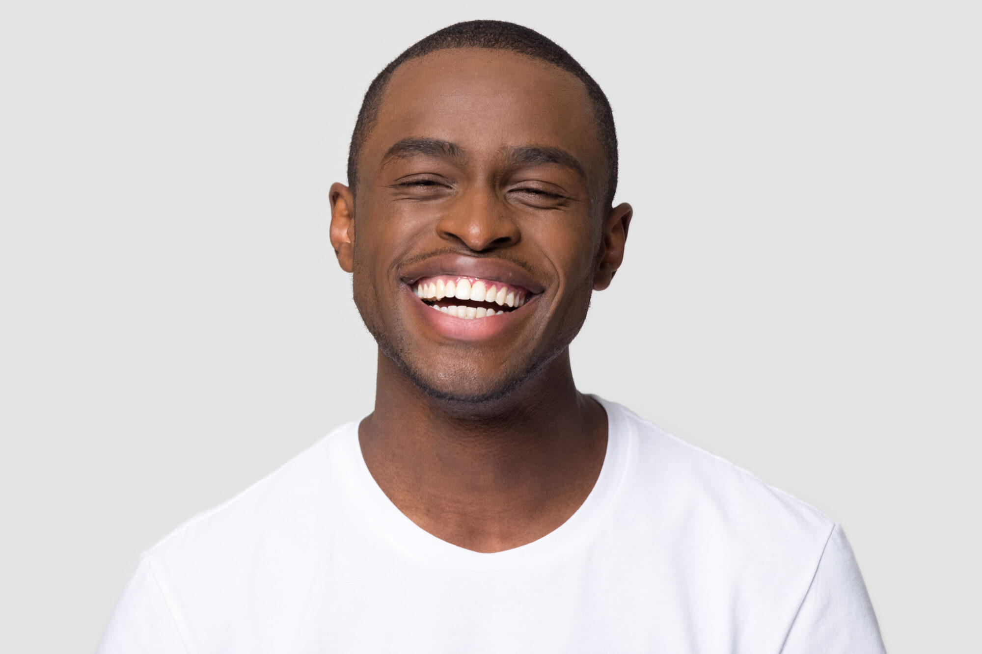 Cheerful happy african millennial man laughing isolated on studio background