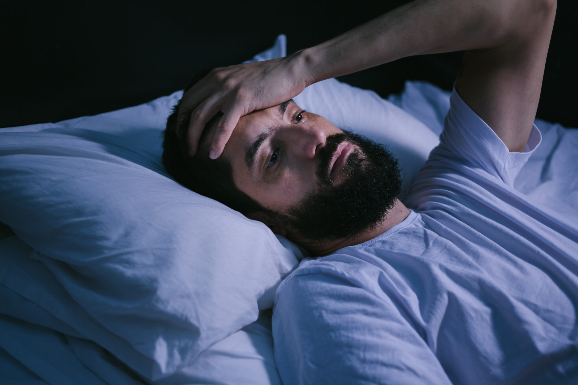 Young man in bed with eyes opened suffering insomnia and sleep disorder