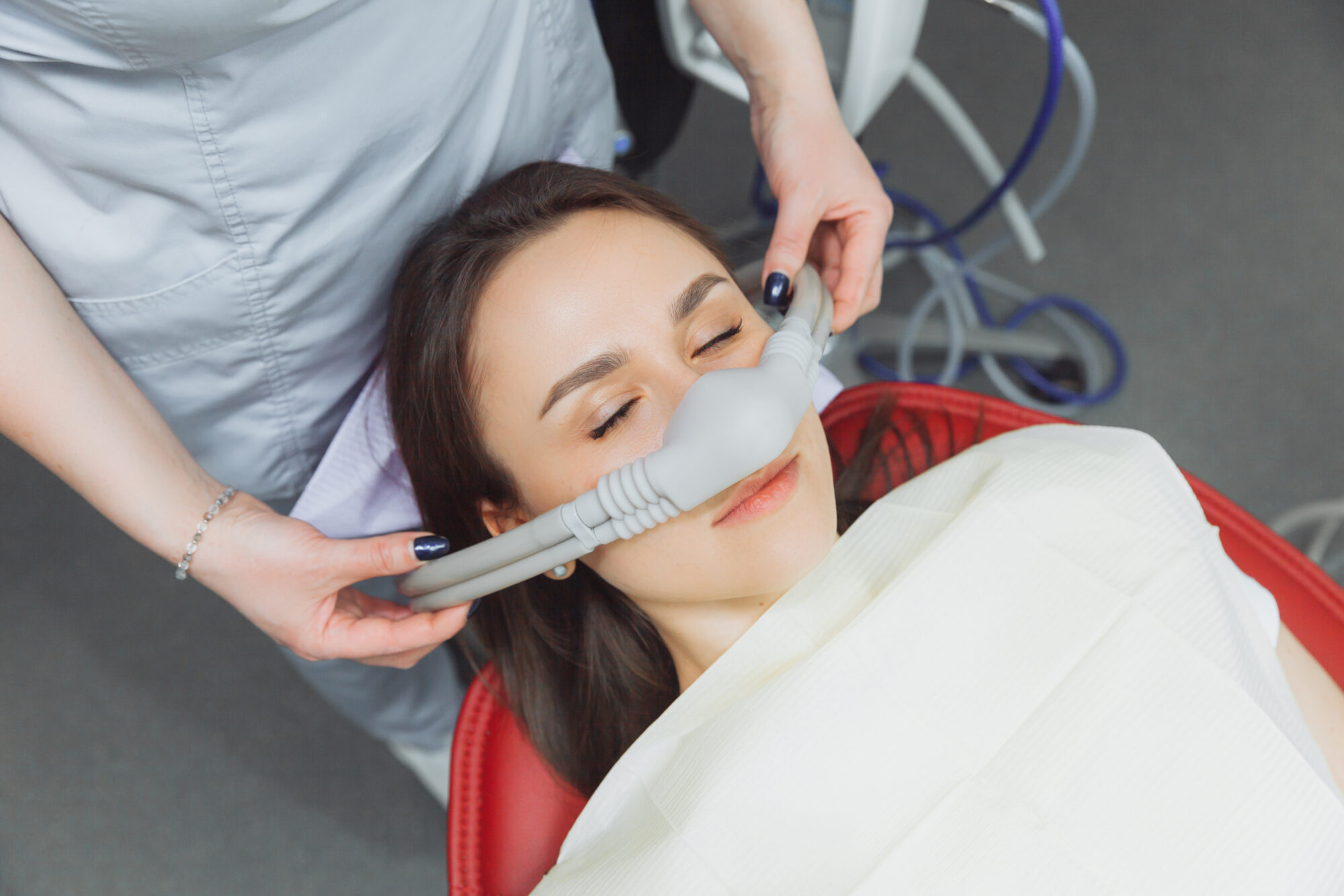 dentist puts inhalation sedative mask on his patient.